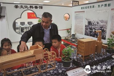 符兴泉正在向孩子们介绍古代制作花茶工具的模型。