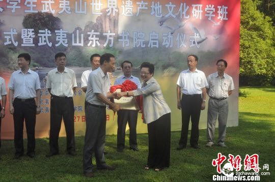 7月28日，2015年闽港大学生武夷山世界遗产地文化研学班启动仪式上，武夷山风景名胜区党工委副书记余泽岚(左)与福建省国际文化中心交流秘书长袁碧鸿(右)进行授牌仪式。　张丽君 摄